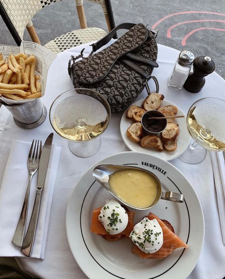 a white plate topped with food on top of a table next to glasses of wine