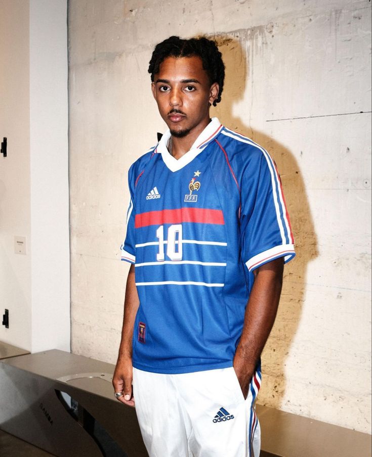 a man standing in front of a bench wearing a blue shirt and white shorts with the number 8 on it