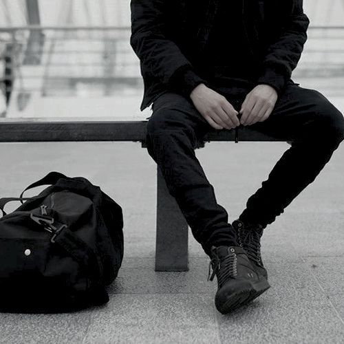 a man sitting on a bench next to a bag