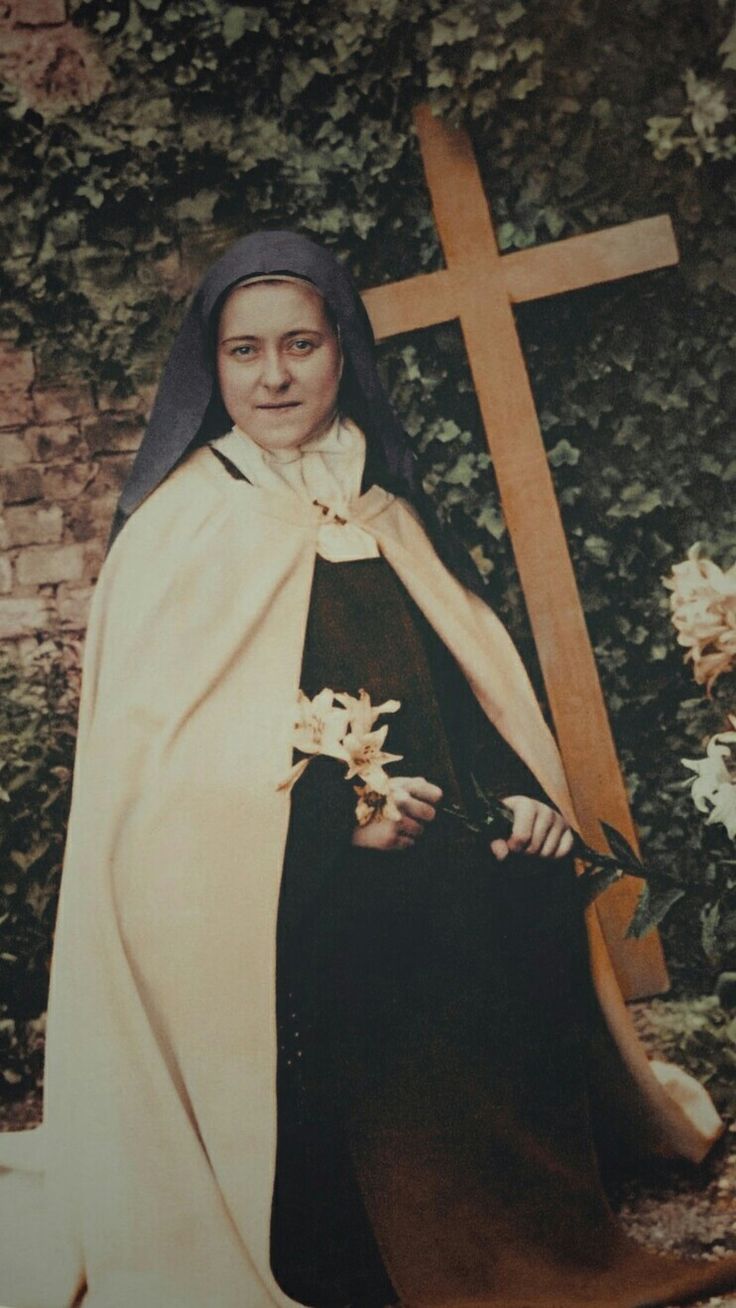 an old photo of a woman dressed in black and white with a cross behind her