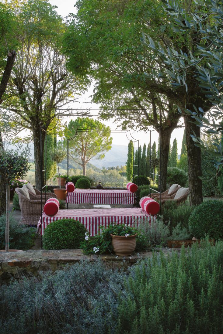 an outdoor seating area with potted plants and striped table cloth on the couches