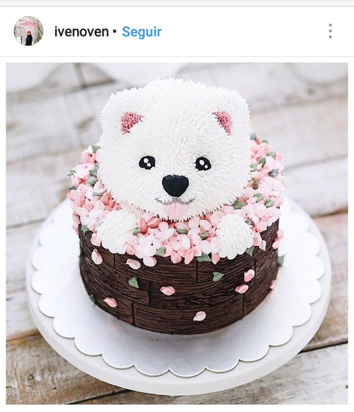 a white teddy bear sitting in a basket with pink flowers on it's head