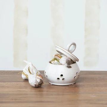 a small white ceramic pot with two garlic cloves in it on a wooden table