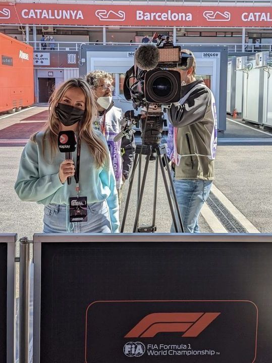 a woman holding a microphone in front of a camera set up on a tripod