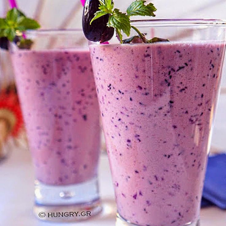 two glasses filled with purple liquid and topped with a green leafy garnish