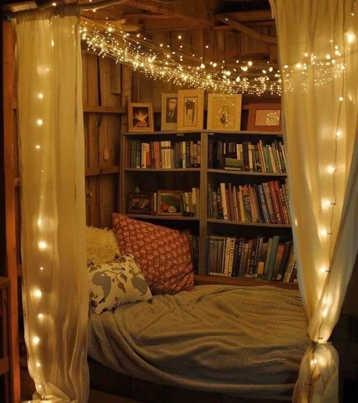 a bed with bookshelves and lights on the ceiling in a room filled with books