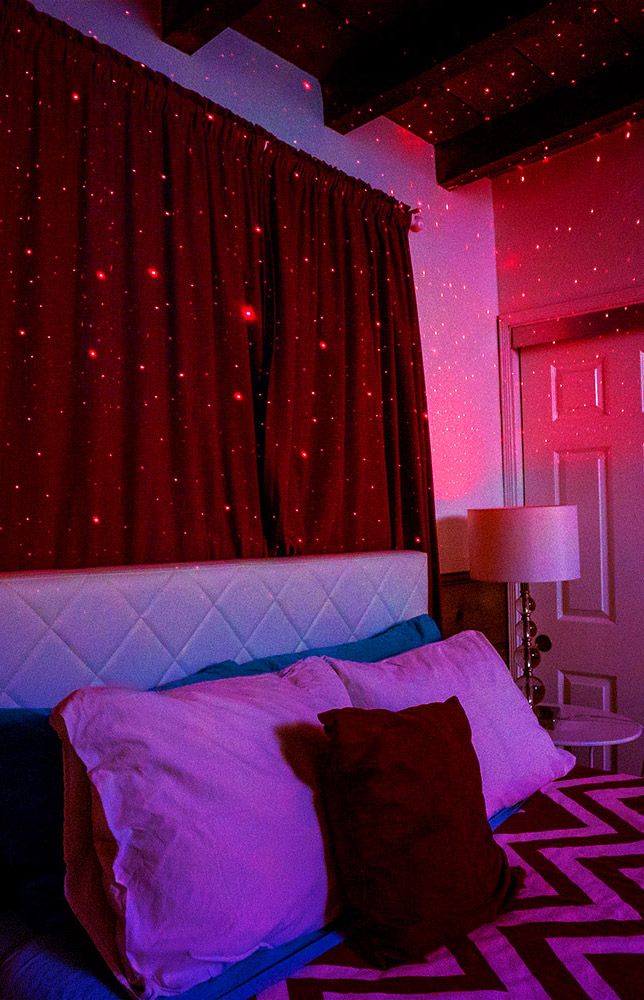 a bed with red and purple lights on the headboard in front of a window