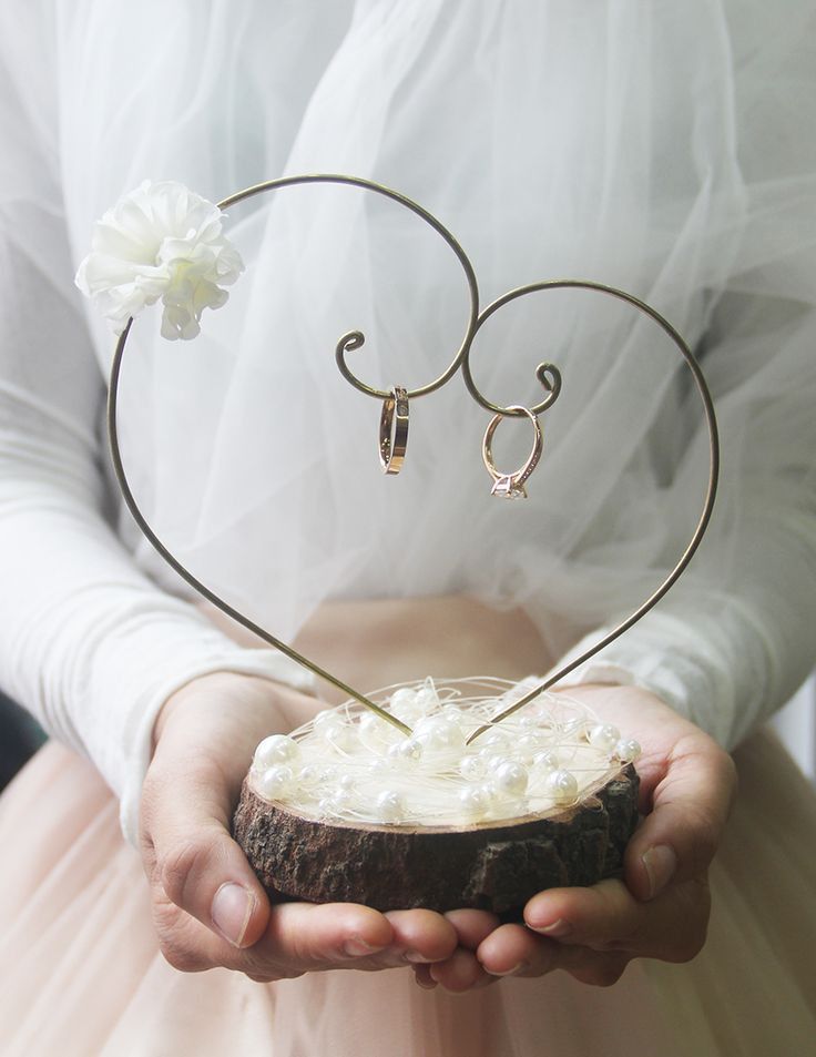 a person in a wedding dress holding a piece of wood with two hearts on it