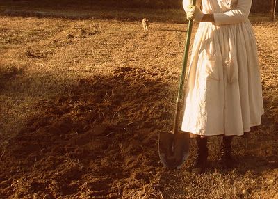 a woman in a white dress is holding a shovel