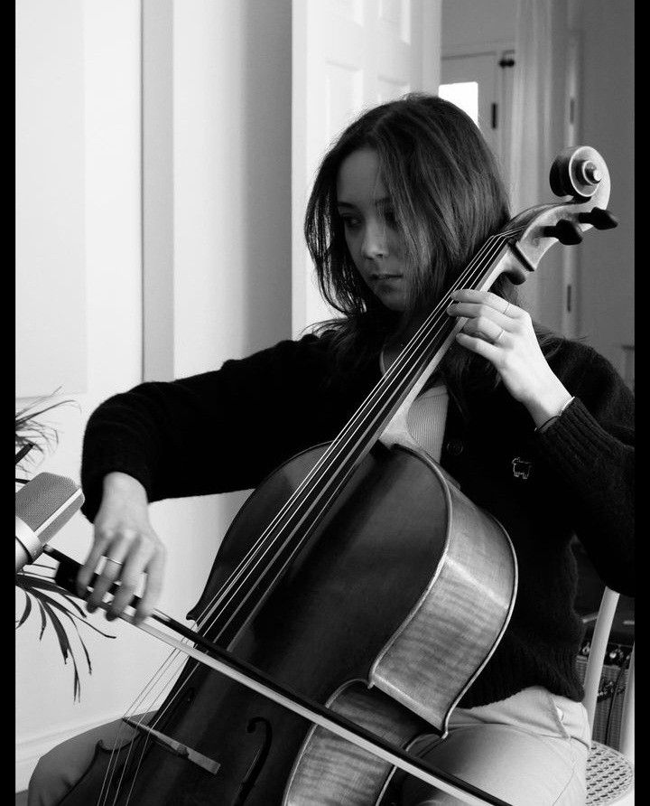 a woman sitting in a chair playing a cello