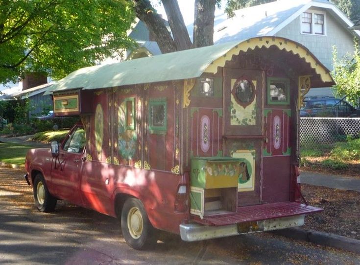 a red truck is parked in front of a house with an awning on it's roof