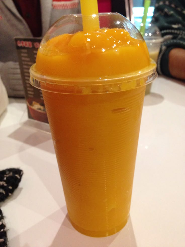 an orange drink in a plastic cup with a straw