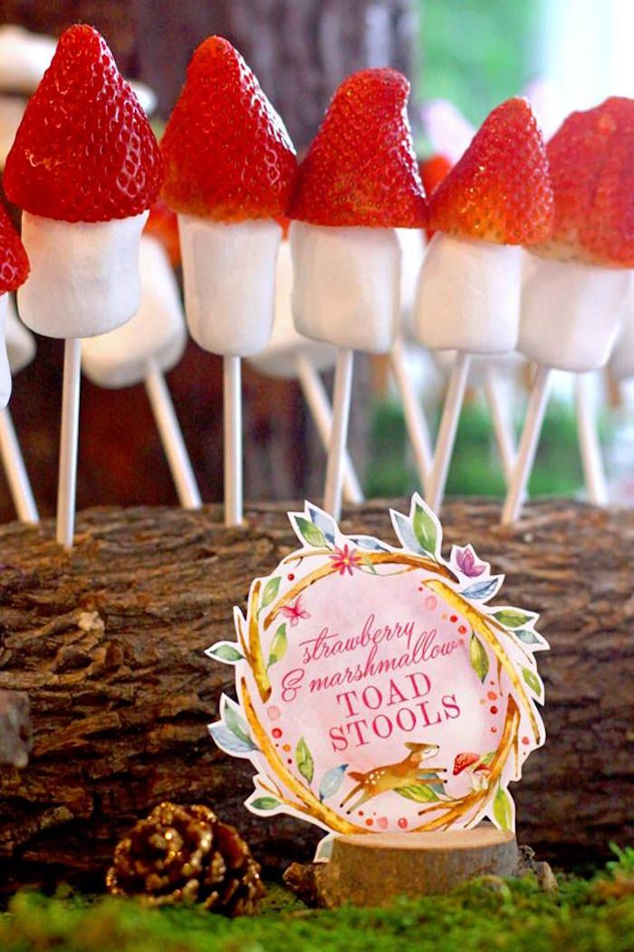 strawberries and marshmallows are on sticks in front of a forest theme