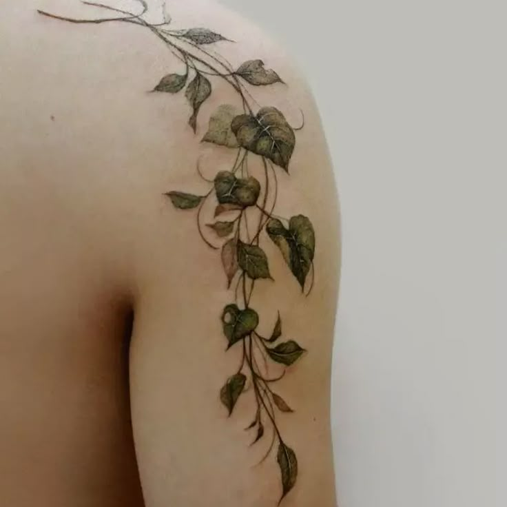 the back of a woman's shoulder with vines on it and leaves growing out of it