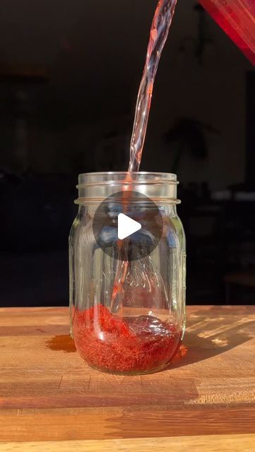 a glass jar filled with red liquid being poured into it