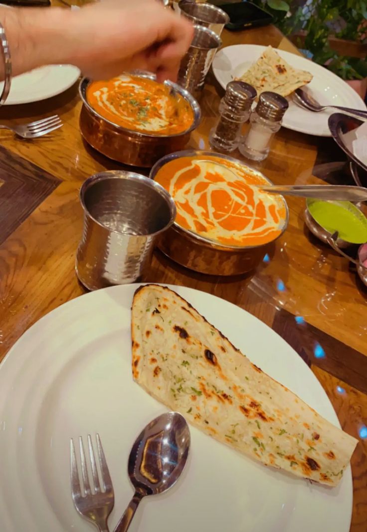 a table topped with plates and silverware filled with food next to bowls of soup