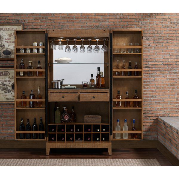 a room with a brick wall and wooden shelves filled with bottles, wine glasses and liquor