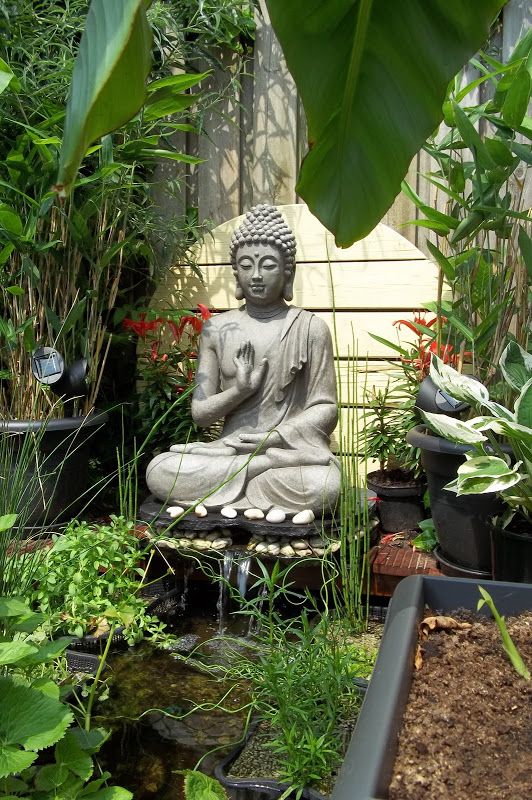 a buddha statue sitting in the middle of a garden