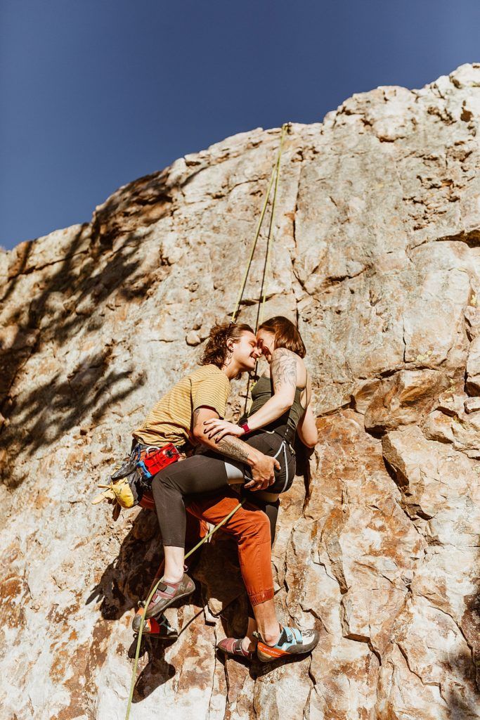 two people climbing up the side of a rock face each other and holding on to ropes