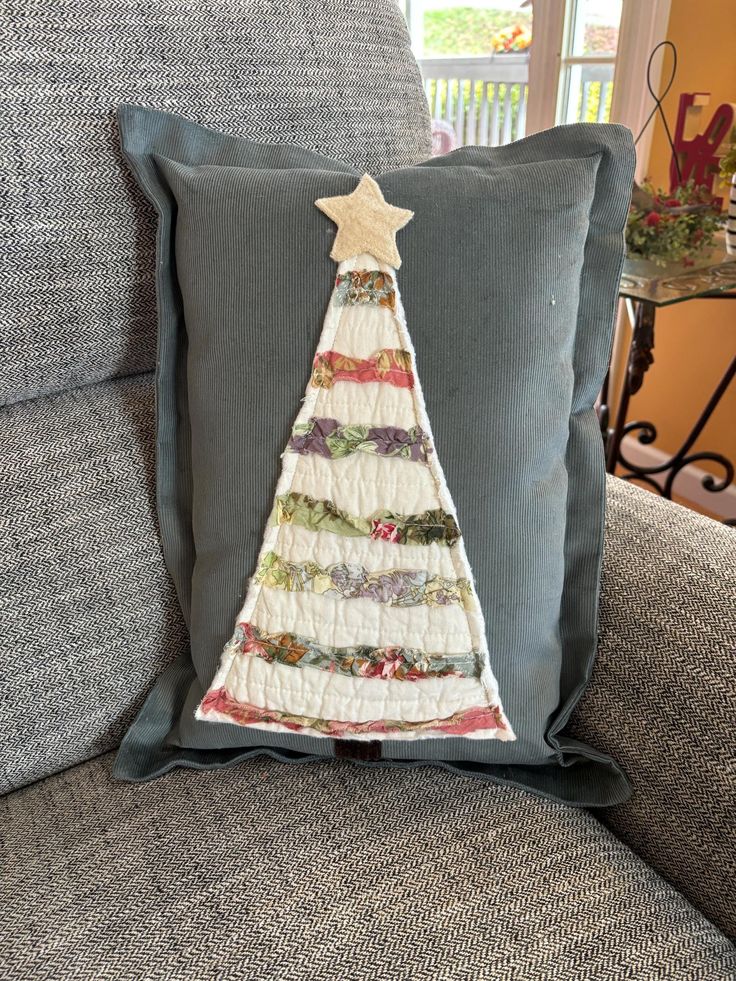 a christmas tree pillow on a couch with a star hanging from it's side