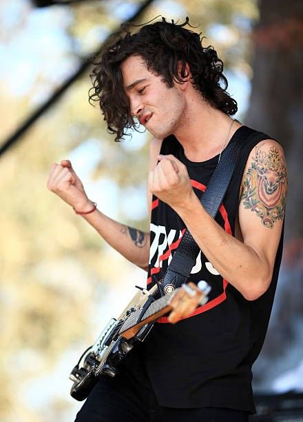 a man with tattoos on his arm playing guitar