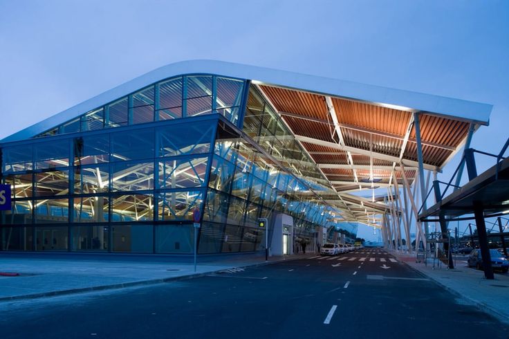 a large glass building sitting on the side of a road next to a parking lot