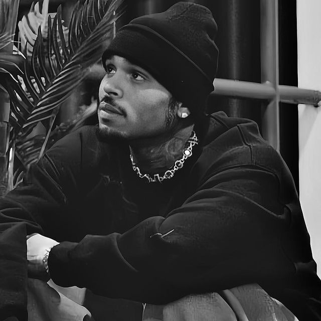 a black and white photo of a man wearing a beanie sitting on a bench