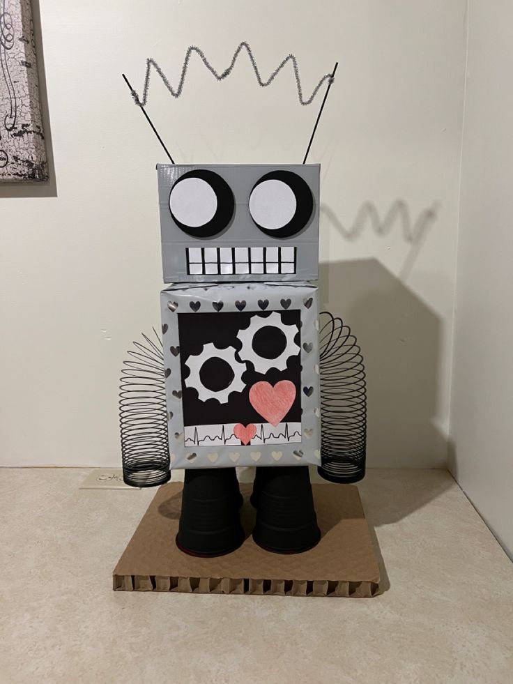 a robot made out of paper on top of a wooden block in the shape of a heart