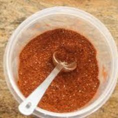 a blender filled with red stuff on top of a counter next to a wooden spoon