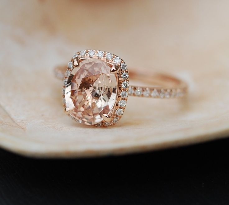 an oval shaped pink diamond ring on a shell