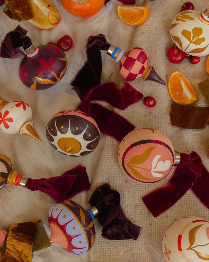 some ornaments are laying out on the ground with ribbon around them and oranges in the background