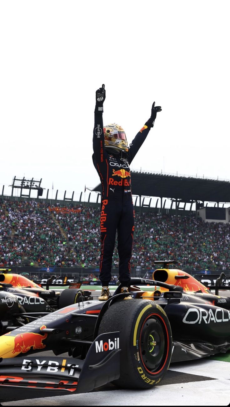 a man standing on top of a race car with his arms in the air and hands up