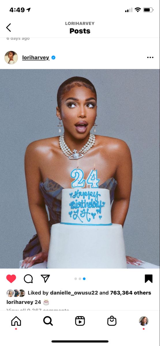 a woman in a dress holding a cake with the number twenty four on it's side