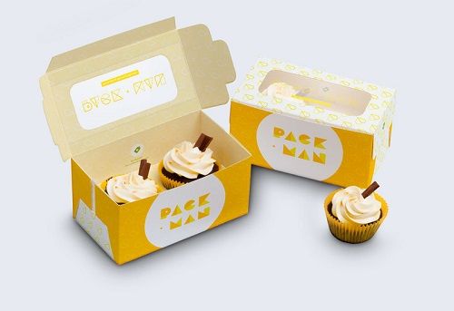 two cupcakes in a yellow box with white frosting on the top and bottom