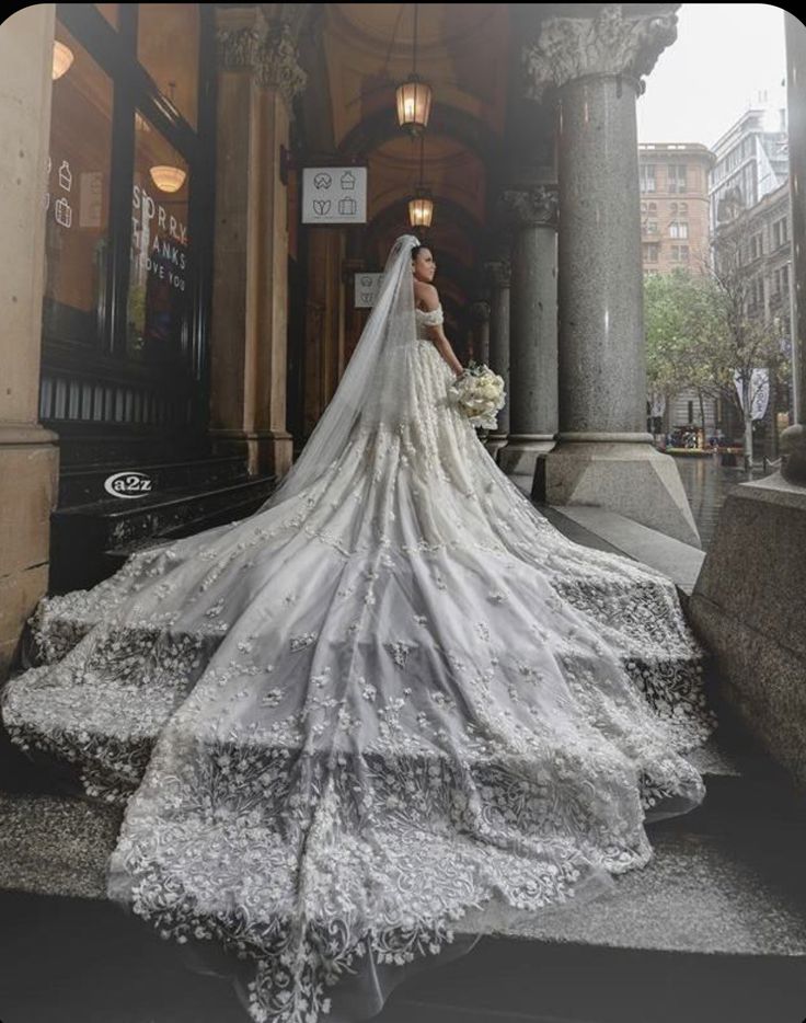 a woman in a wedding dress is standing on the steps outside an old building with columns