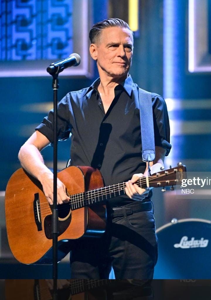 a man with an acoustic guitar on stage