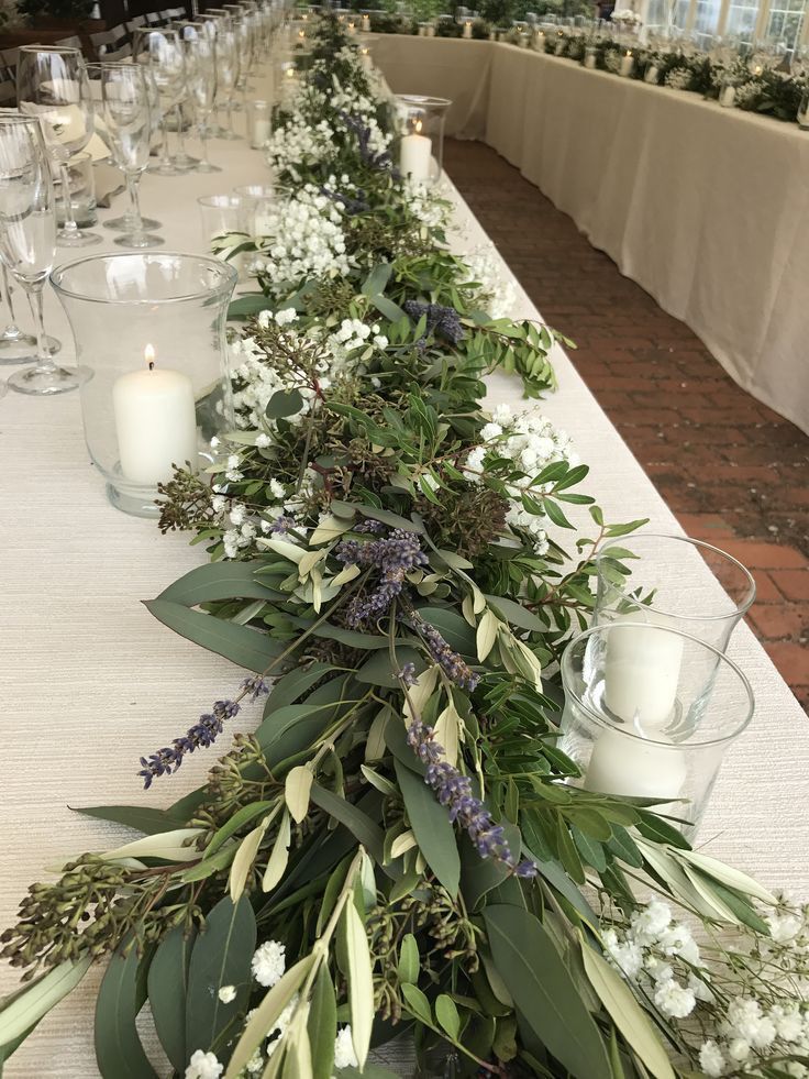 a long table with candles and greenery on the top is set up for a formal function