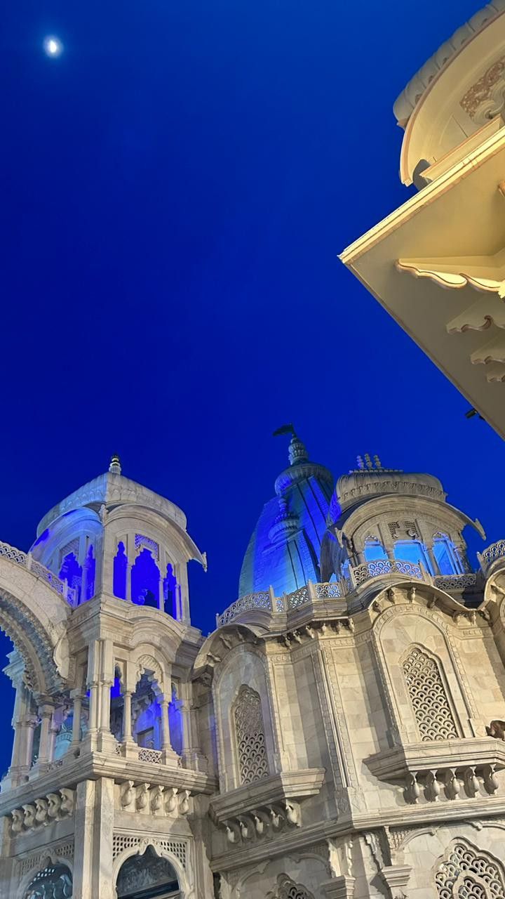 an ornate building lit up at night with the moon in the sky above it and below