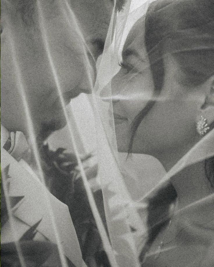 a man and woman standing next to each other with veils over their heads in front of them