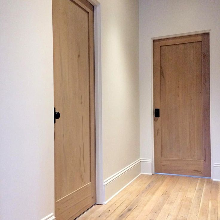 an empty room with two wooden doors and hard wood flooring on the other side