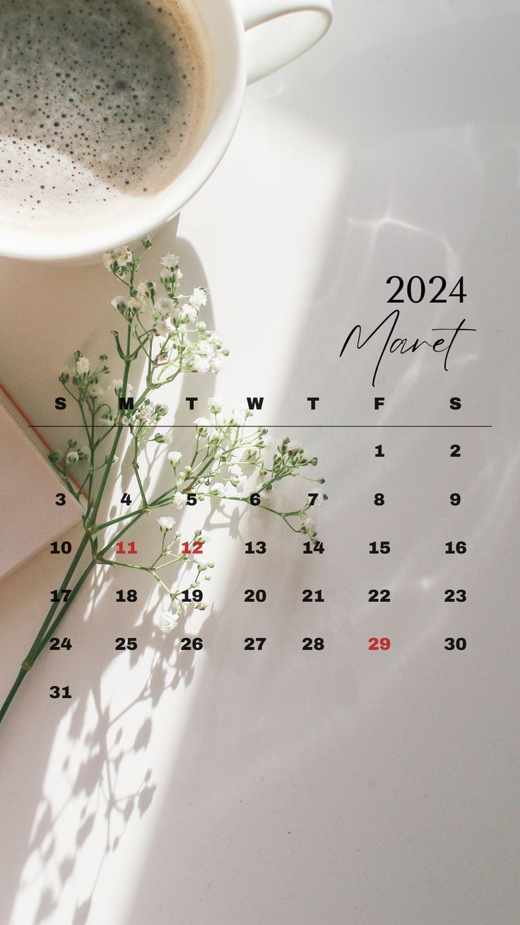 a cup of coffee sitting on top of a table next to a calendar