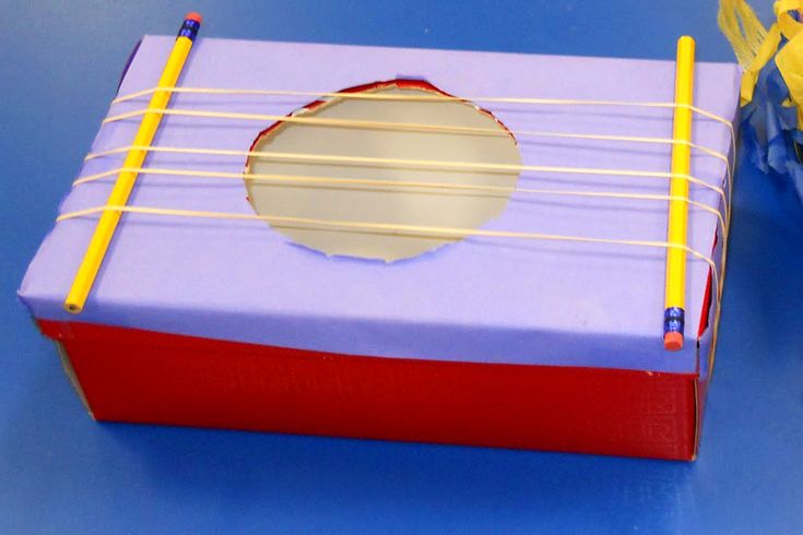 a purple box with yellow and red strings attached to it, sitting on a blue surface