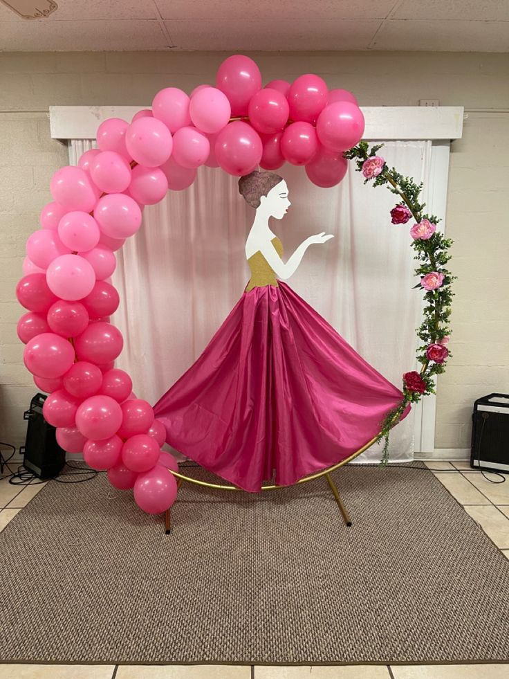 there is a pink balloon arch with a woman in it