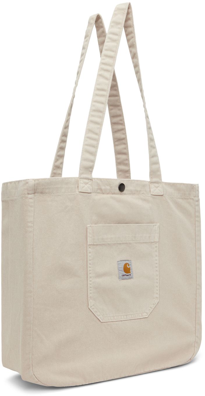 Heavyweight stone-dyed cotton twill tote in beige. · Fading throughout · Fixed carry handles · Patch pocket and logo patch at face · Press-stud closure · Zip pocket at interior · Unlined · H15 x W15.5 x D5.5 Supplier color: Tonic Wip Bag, Carhartt Work In Progress, Bag Suitcase, Denim Tote, Brown Shoulder Bag, Carhartt Wip, Work In Progress, Cotton Tote Bags, Patch Pocket