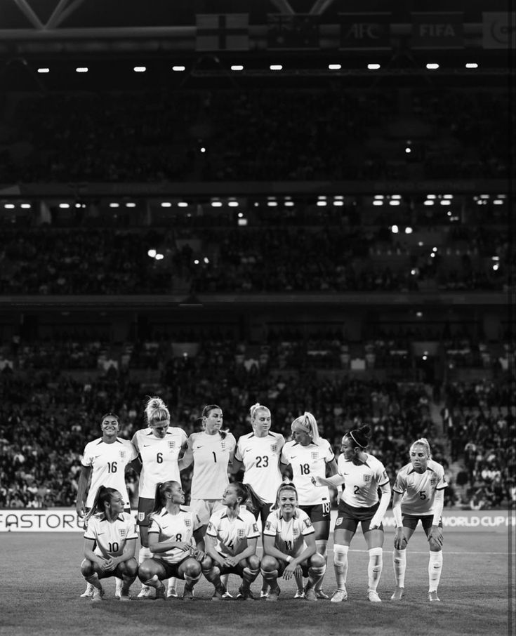 a group of women's soccer players pose for a team photo in front of an audience