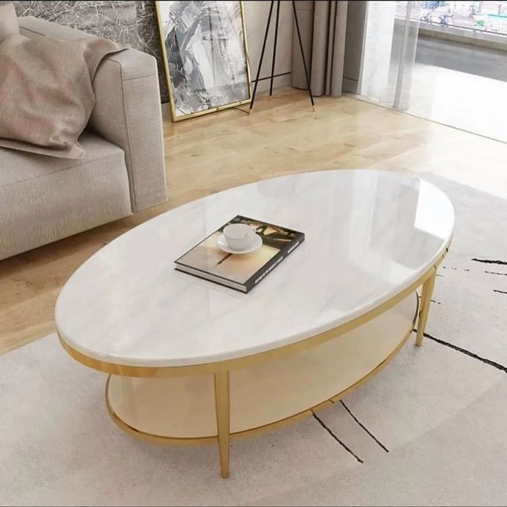 a white marble coffee table with gold trim around the top and bottom, in front of a beige couch