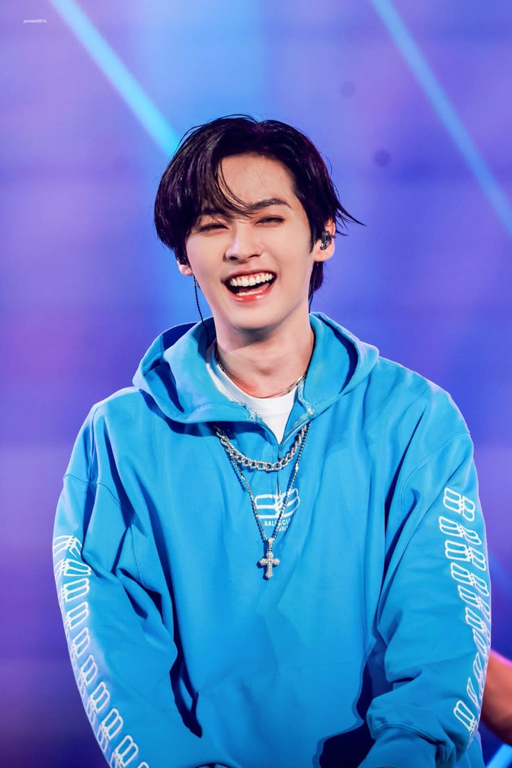 a young man wearing a blue hoodie and smiling