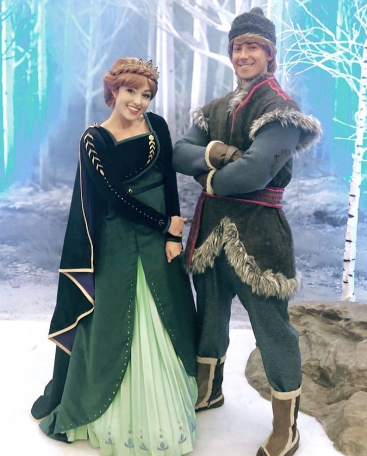 a man and woman dressed in costumes standing next to each other on snow covered ground