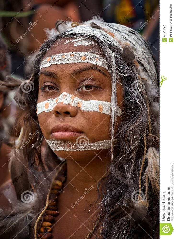 a native american girl with white paint on her face and headdress, looking at the camera