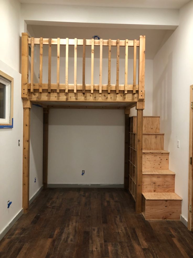 an empty room with wooden stairs and hard wood flooring on the bottom half of it